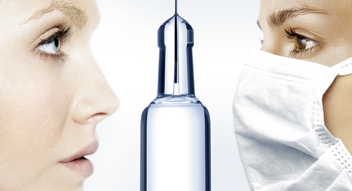 Two females looking at the top of a clear glass pharmaceutical syringe