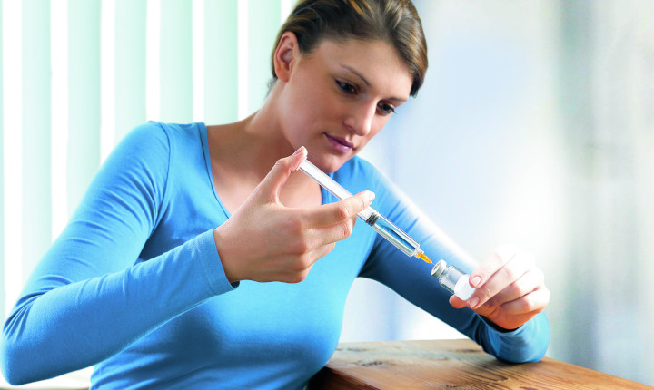 Woman injecting a liquid into a glass ampoule