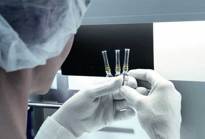 A scientist looking at a series of glass ampoules