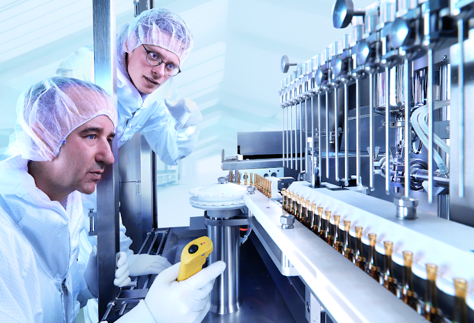 Two scientists looking at glass processing equipment