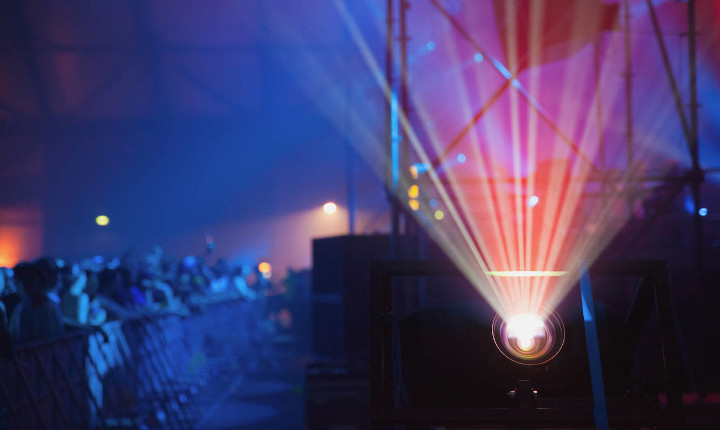 Digital projector in a music venue projecting laser light using aspherical lenses