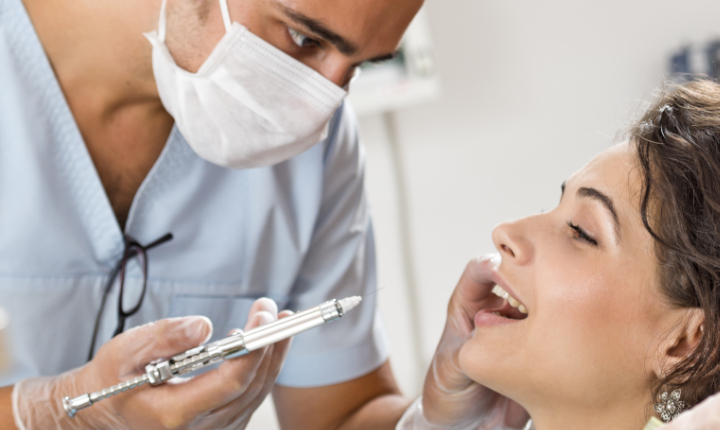 Male dentist about to inject a female patient using a syringe