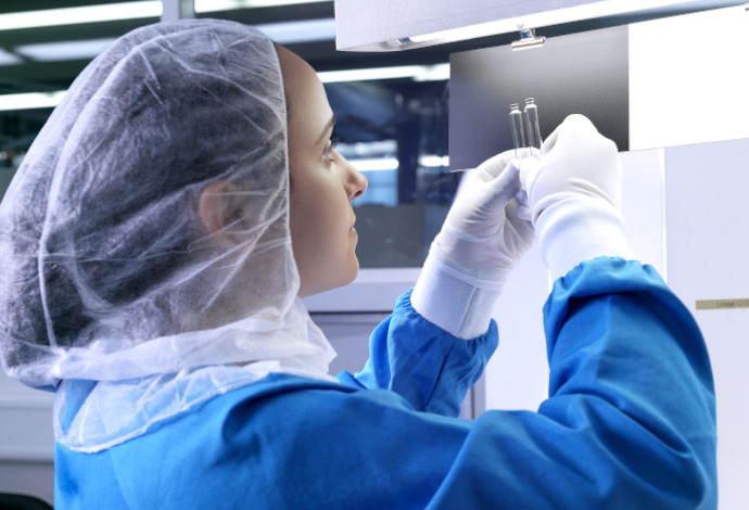 Scientist inspecting a small clear glass pharmaceutical cartridge