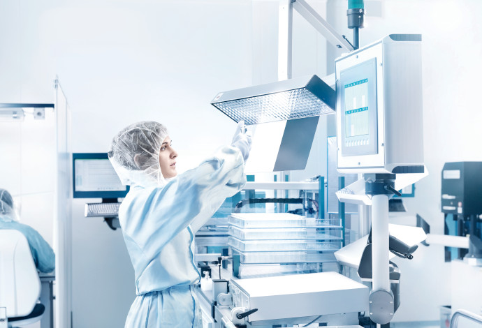 Scientist inspecting several clear glass pharmaceutical cartridges