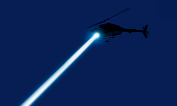Helicopter shines searchlight down onto a city at night