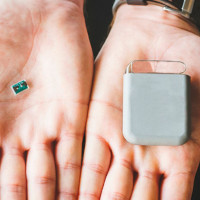 Two hands, one with a large medical implant, the other with a tiny implantable device using glass micro bonding technology offered by SCHOTT Primoceler