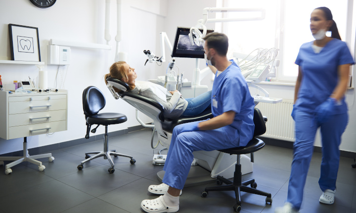 Dentist sits next to a patient