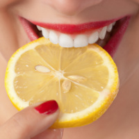 Female mouth biting into a lemon slice