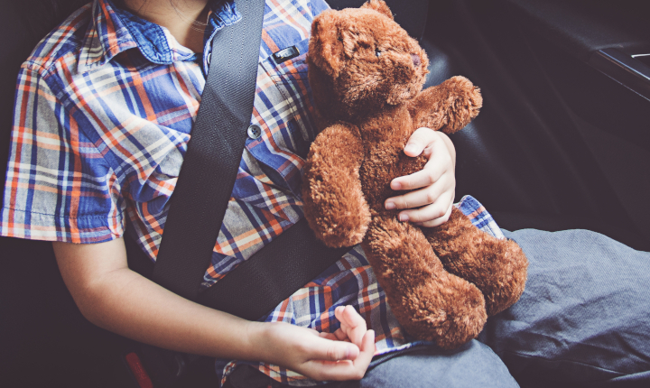 Child sitting in vehicle secured with a seatbelt