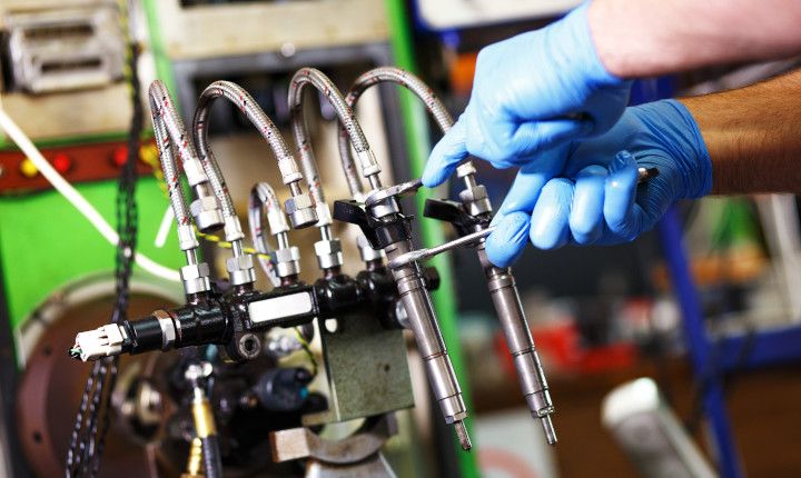 Professional mechanic testing diesel injector in a workshop