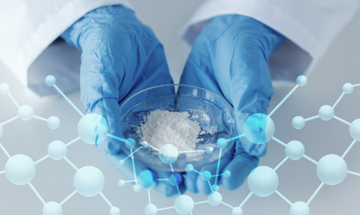 Close up of a scientist holding a petri dish filled with glass powder in a laboratory	