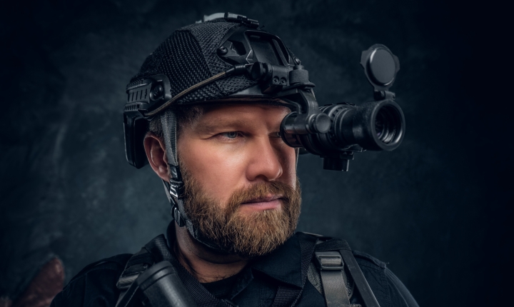Close-up portrait of a bearded special forces soldier looking through a pair of night vision goggles