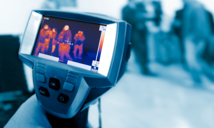 Thermal imaging camera in the foreground monitoring people in a monochrome background