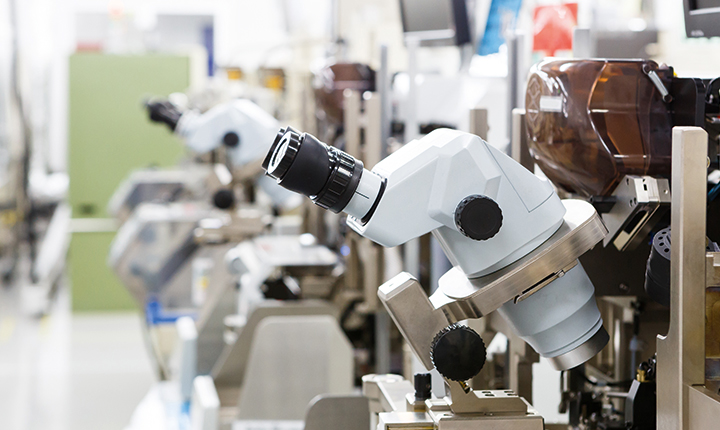 A row of stereo microscopes in a manufacturing laboratory