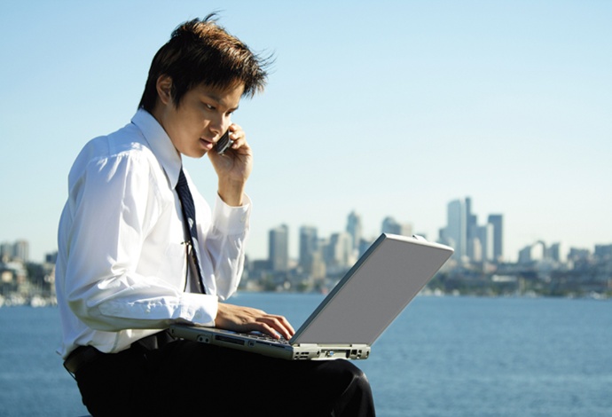 Young businessman working on laptop with city in background