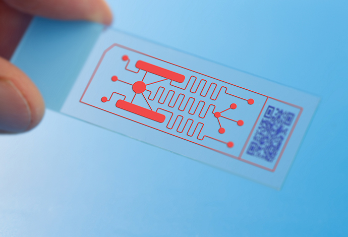 SCHOTT MEMpax® is ideal for lab-on-a-chip systems in diagnostics and life science applications Hand holding an ultra-thin glass sheet with lab-on-a-chip system
