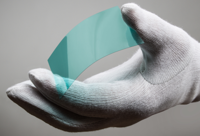 Hand with white glove holds curved blue glass