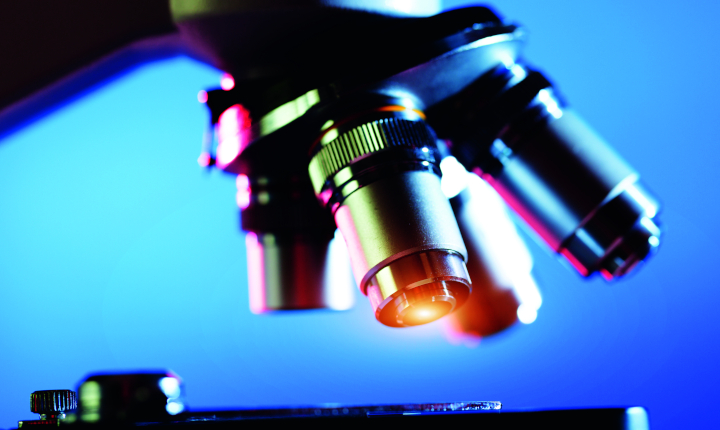 Close up of four microscope lenses on a blue background