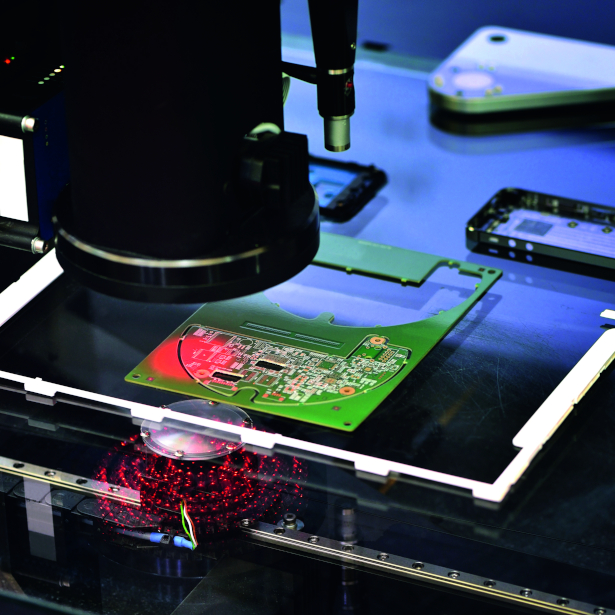 Small, green microchip being inspected by machine vision equipment