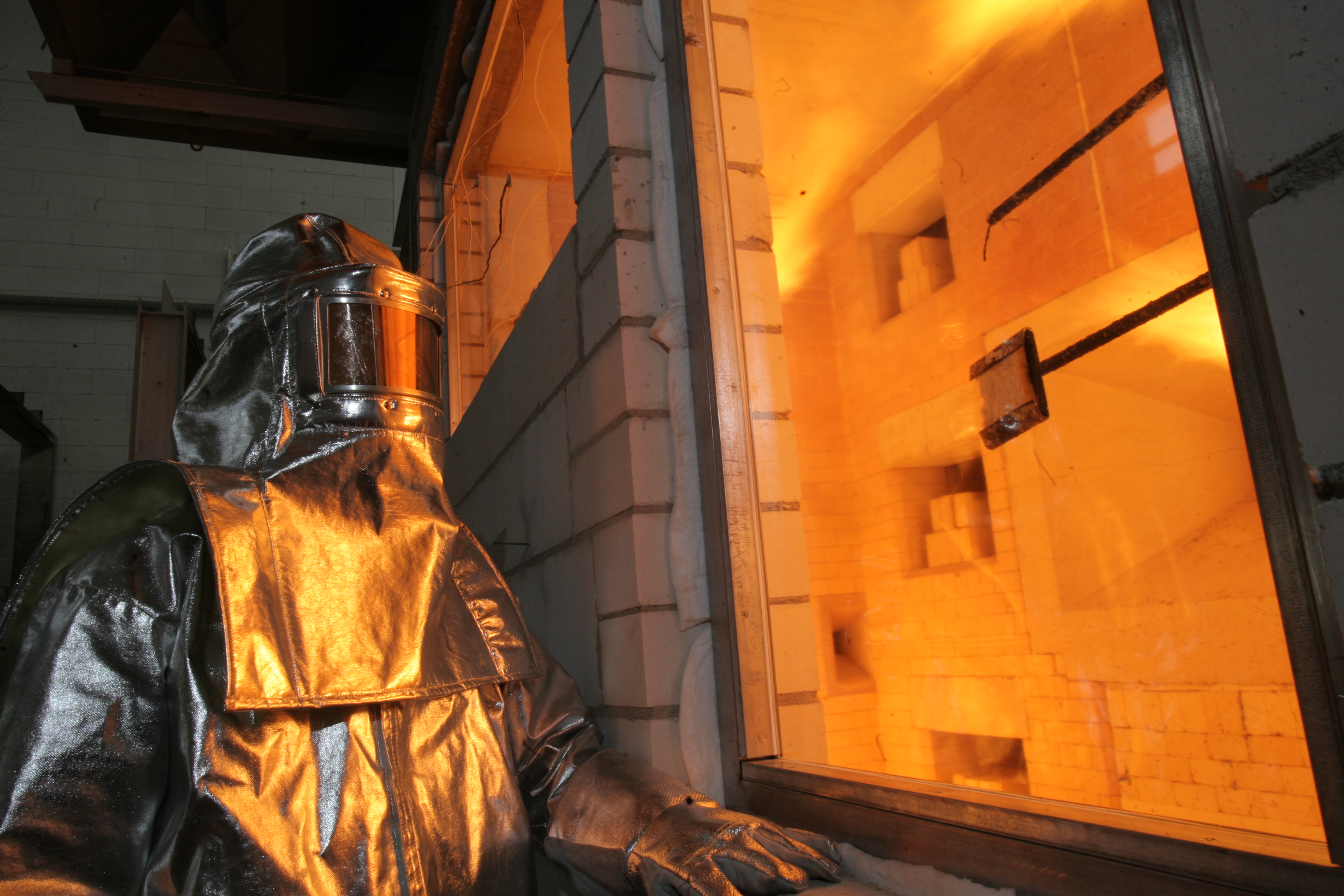 Engineer in heat-resistant suit conducting a fire test on glass 