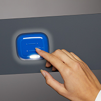 A hand touching on a blue SCHOTT Jade Reading Light