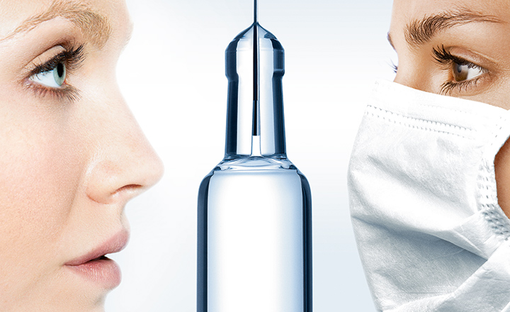 Two females looking at the top of a clear glass pharmaceutical syringe