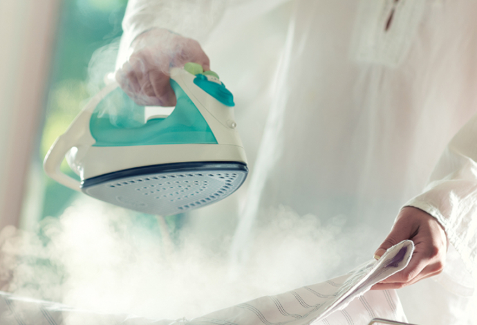 Person in white shirt using a domestic iron