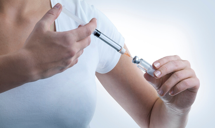 Woman in white t-shirt using a syringe to draw medication from a cartridge