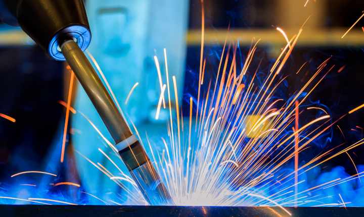 Robot arm welding metal in an industrial setting
