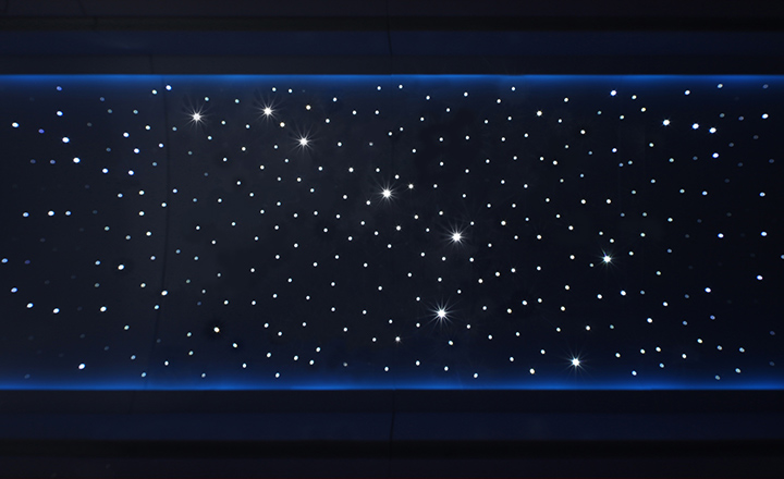 Ceiling of an aircraft cabin at night lit up by SCHOTT's Star Ceiling illumination system