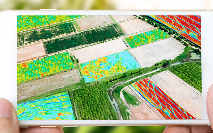 Mains tenant un smartphone avec une image aérienne du paysage	