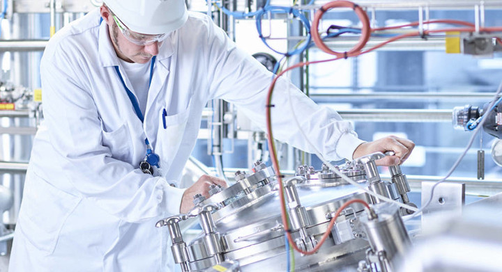 Man in white overalls and hat working in an industrial plant	