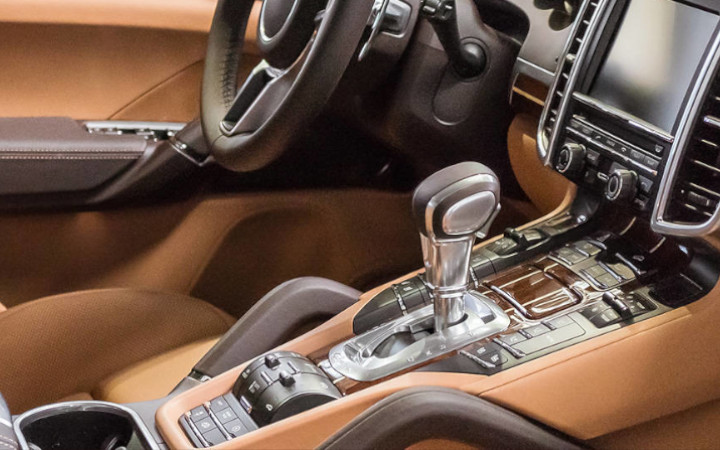 Brown interior of a luxury vehicle with dashboard, steering column and gear stick