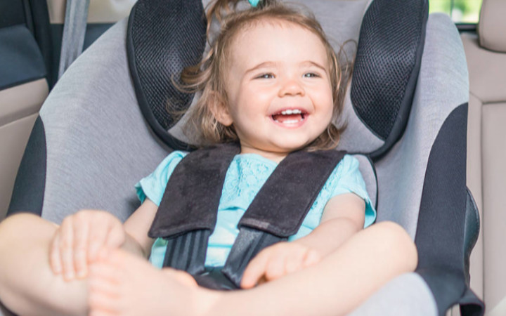 Small baby in a child seat in the back of a luxury vehicle