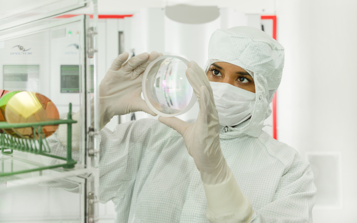 Female scientist inspecting a clear glass disc in a laboratory