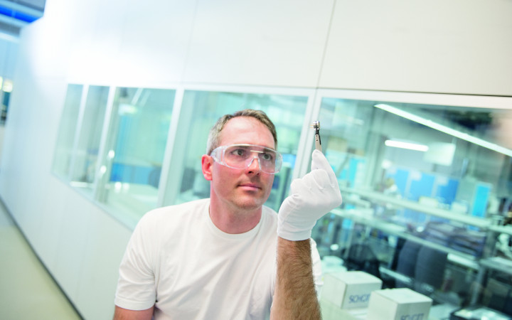 Male scientist inspects a glass-sealed sensor feedthrough in a laboratory
