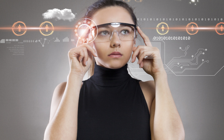 Young female wearing augmented reality glasses looking at computer-generated information