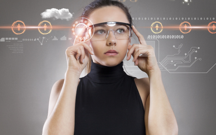 Young female wearing augmented reality glasses looking at computer-generated information