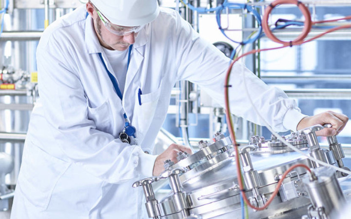 Man in white overalls and hat working in an industrial plant