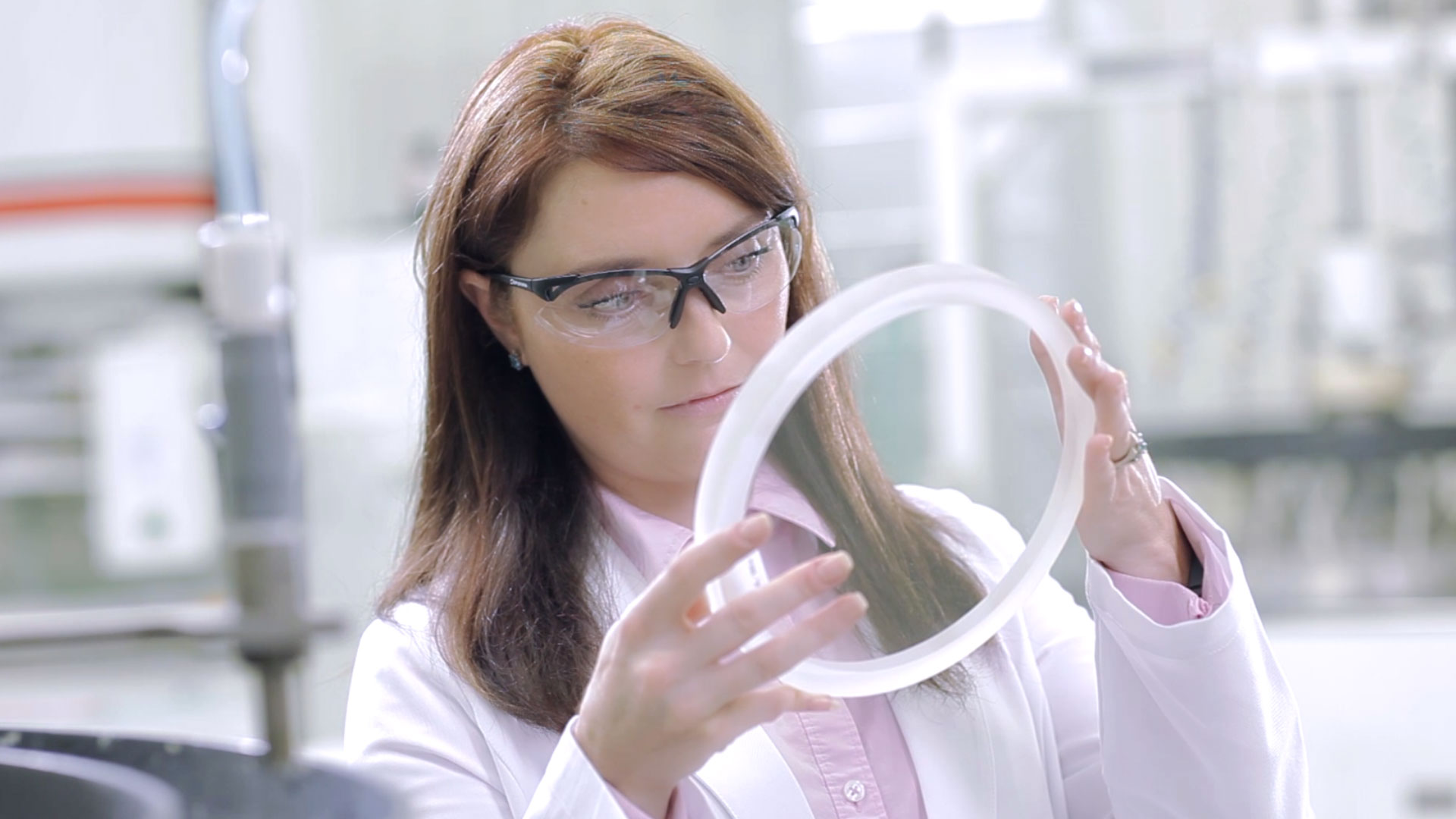 Female scientist examining a large circular sight glass in a laboratory