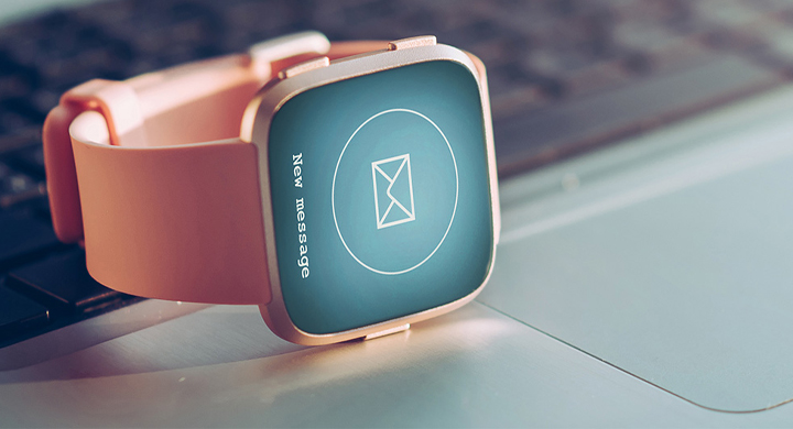 SCHOTT provide a range of components for mobile and wearable devices Smartwatch with an orange strap on top of a silver laptop computer