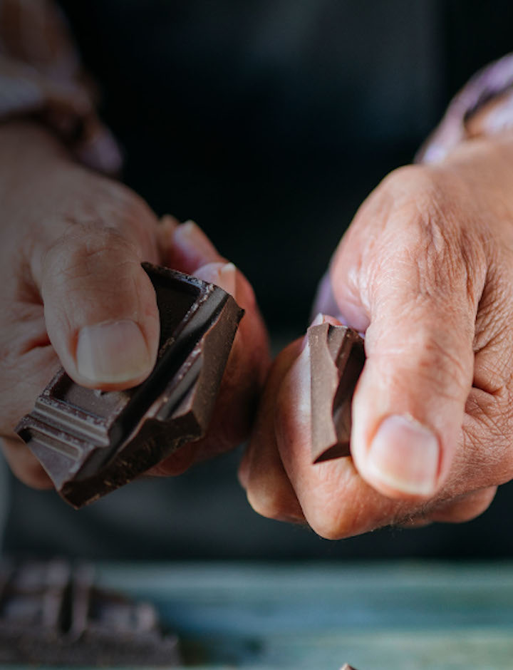 Pair of elderly male hands breaking a piece of chocolate