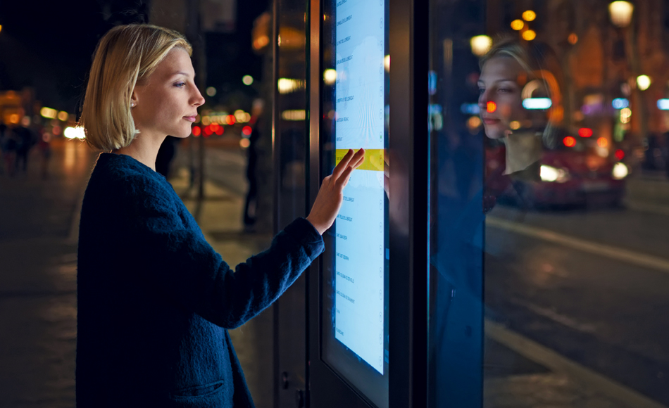 Female looking at an outdoor digital display at night